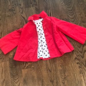 A button up jacket with dogs and a bow on the back